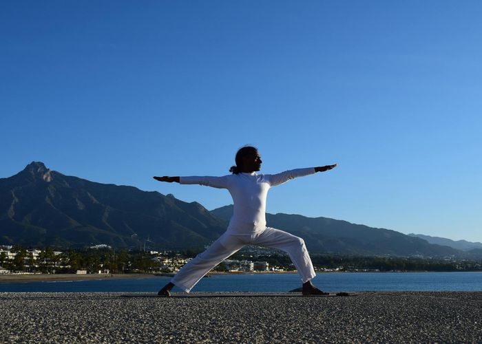Silhouette of a person in a powerful yoga warrior pose at sunrise.